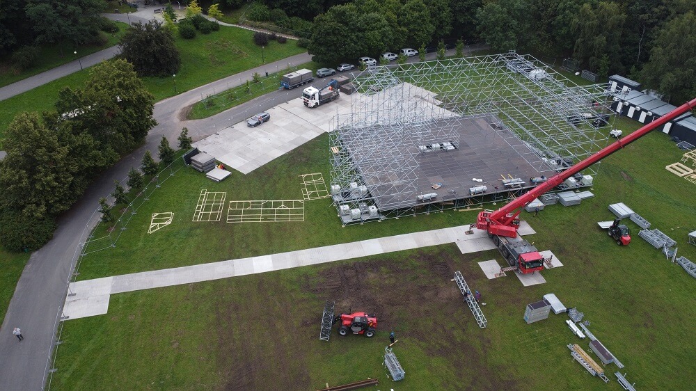 Budowa dużej sceny plenerowej: stalowa konstrukcja, dźwig i sprzęt na trawniku