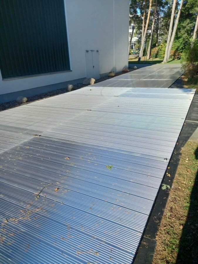 Zewnętrzna ścieżka wyłożona metalowymi panelami, z drzewami w tle i budynkiem wzdłuż krawędzi.