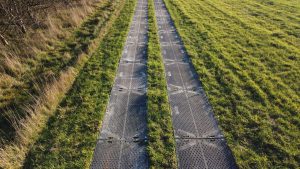 Dwujezdniowa droga z metalowymi panelami, otoczona zielonym trawnikiem i łagodnymi brzegami.