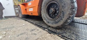 Widok na dużą oponę wózka widłowego stojącego na metalowej platformie na budowie.