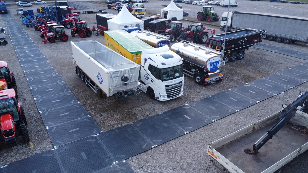 Na zdjęciu widać teren wystawy rolniczej z ciągnikami i ciężarówkami, w tym cysterny i naczepy.
