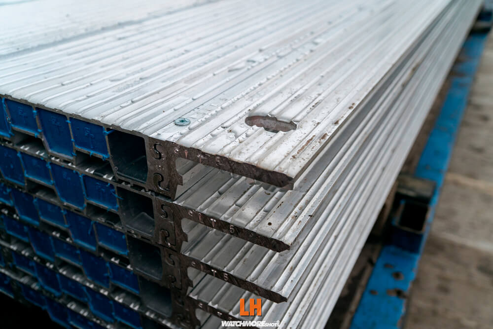 Stos metalowych elementów z wycięciami, układanych na niebieskiej podstawie.