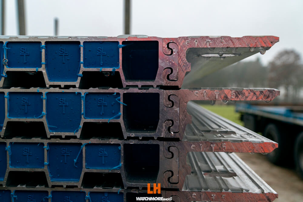 Zdjęcie przedstawia stos stalowych profili z wyraźnie widocznymi niebieskimi i metalicznymi elementami.