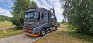 Ciężarówka Volvo stojąca na drodze, transportująca materiały budowlane, w otoczeniu zieleni.