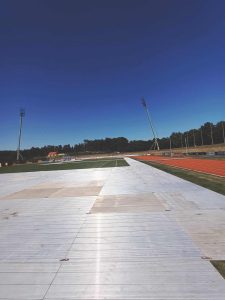 Widok na stadion z torami biegowymi, z płaską powierzchnią i jasnym niebem w tle.