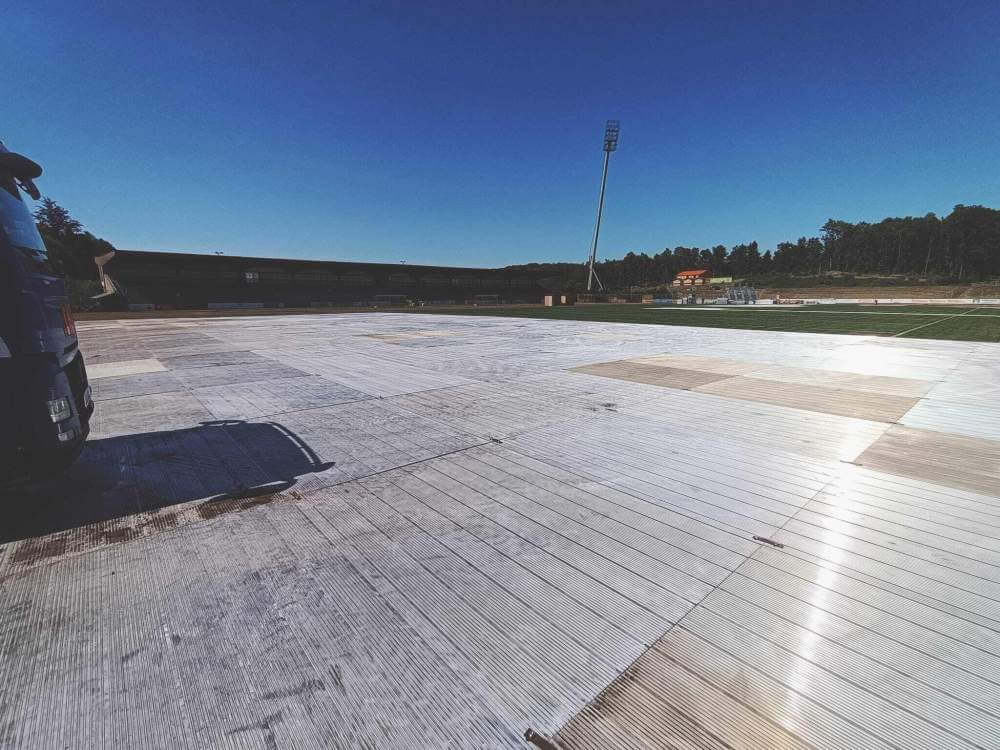 Widok na przygotowane boisko sportowe z białą nawierzchnią pod płaskim, błękitnym niebem.