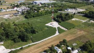 Widok na obszar z wieżą komunikacyjną wśród pól uprawnych i zabudowy wiejskiej.