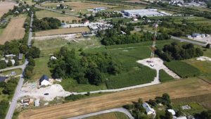 Widok z lotu ptaka na teren wiejski z drzewami, polem i małymi budynkami oraz wieżą telekomunikacyjną.